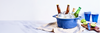 Blue tub of ice holding beer bottles and cans on a striped cloth; lime halves, cutting board and blue cups beside.
