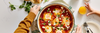 Shakshuka with eggs, herbs, and cheese served in a pan on a dining table