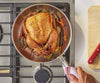 A bird’s eye view of a whole roasted chicken with roasted vegetables in a Misen Stainless Steel Pan on a stovetop.