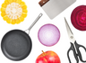 Black nonstick frying pan, red apple, halved red onion, sliced beet, yellow squash slice, kitchen shears, metal spatula.