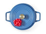 Top-down view of round blue lidded pot with brass knob and red gift bow on lid.
