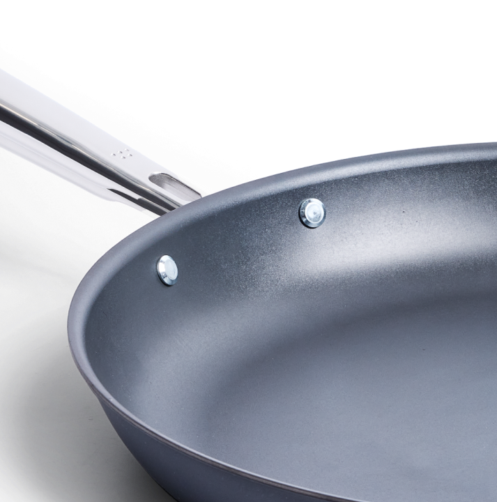 Hard anodized nonstick frying pan with stainless steel riveted handle close-up