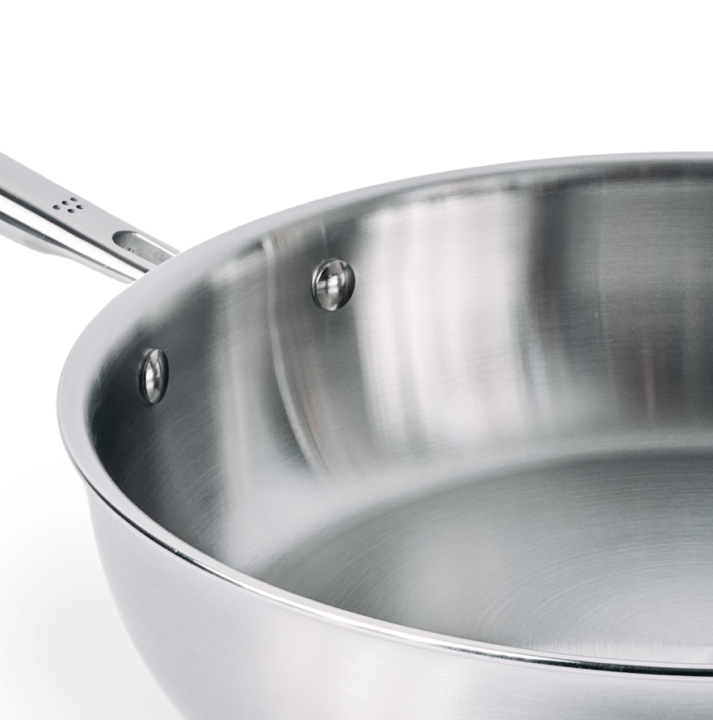 Stainless steel frying pan interior with riveted handle close-up