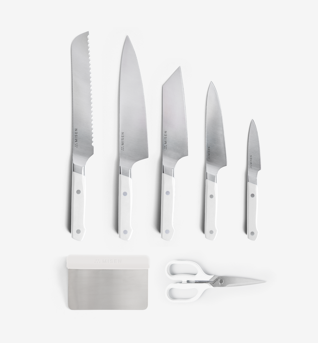 Misen 7-piece kitchen knife set with white handles including bread, chef, santoku, utility, and paring knives plus bench scraper and shears