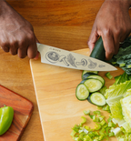 Misen chef's knife with mushroom etching slicing cucumber on wooden cutting board