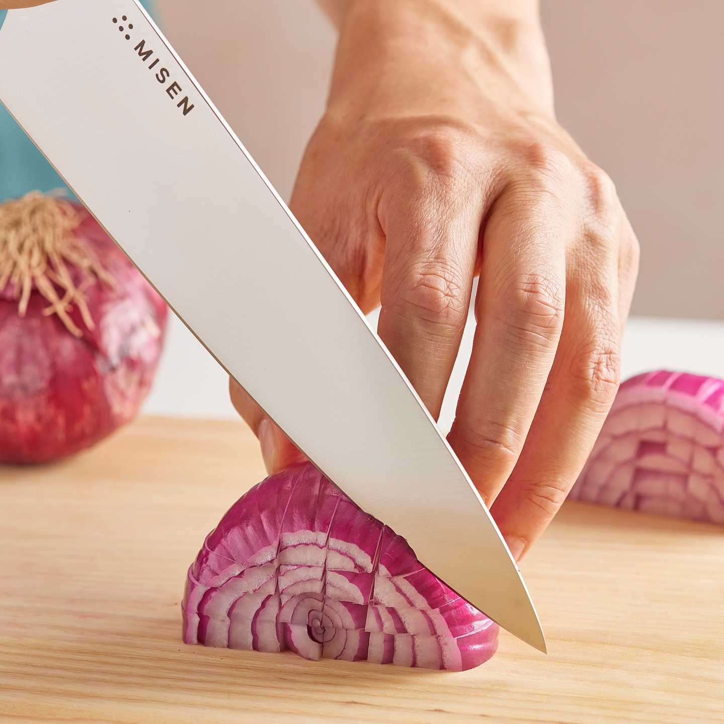 Misen chef's knife dicing a red onion on a wooden cutting board