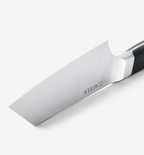 Misen chef's knife blade close-up showing polished stainless steel and bolster