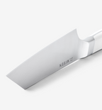 Misen chef's knife blade close-up showing polished stainless steel and bolster