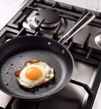 Fried egg cooking in nonstick skillet on gas stove
