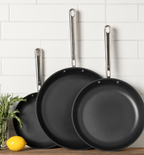 Three-piece nonstick frying pan set with stainless steel handles on kitchen counter