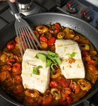 Pan-seared halibut fillets with burst cherry tomatoes and fresh mint in skillet
