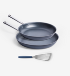Two nonstick ceramic fry pans stacked with stainless steel handles and a slotted spatula