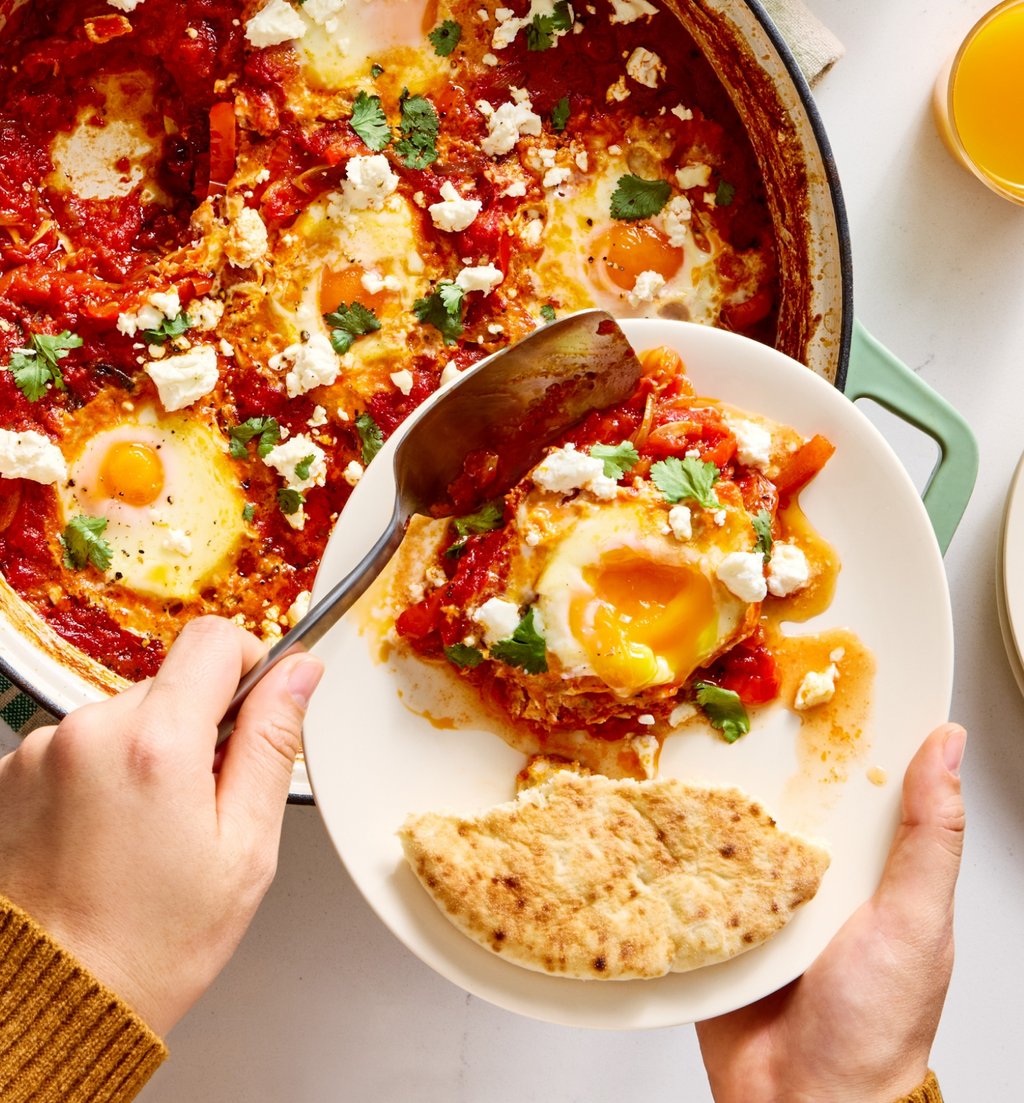 Shakshuka with feta cheese and fresh herbs served in a cast iron skillet