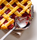 Homemade cherry pie with golden lattice crust in a Misen baking pan, partially served