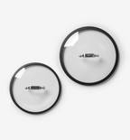 Two glass pot lids with stainless steel handles and black silicone rims, different sizes