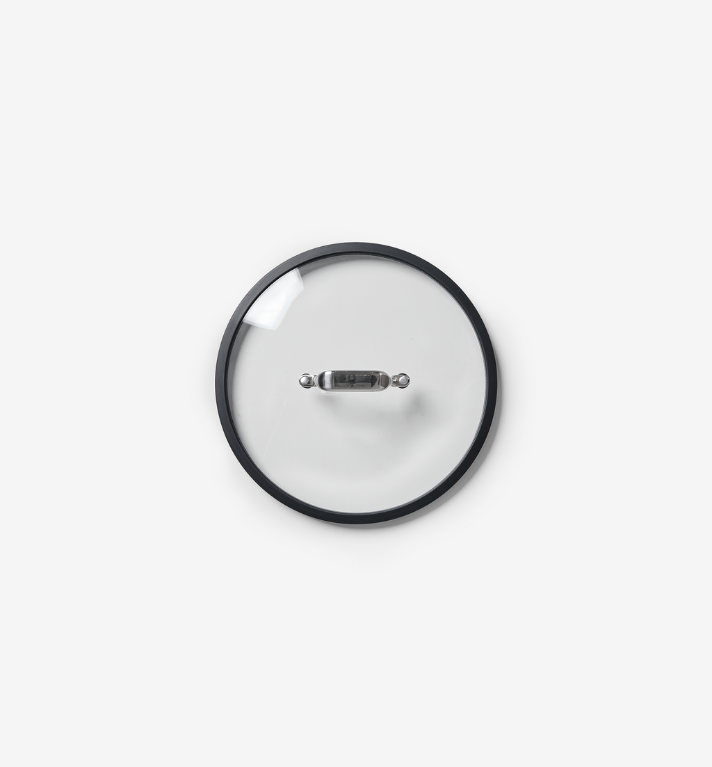Glass cookware lid with stainless steel handle and black silicone rim, top view