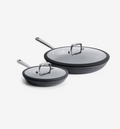 Two dark gray nonstick frying pans with glass lids and stainless steel handles, small and large sizes