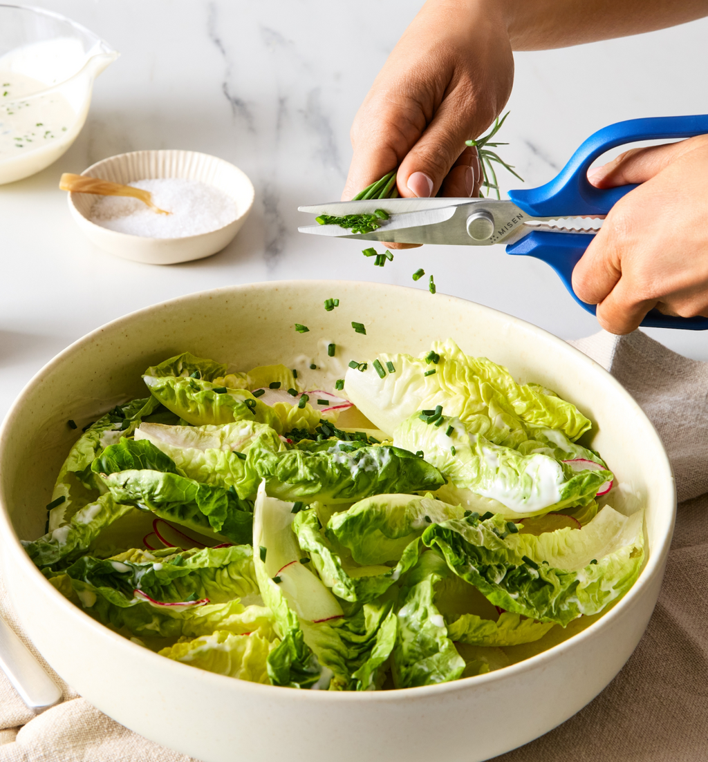 Snipping fresh chives over romaine lettuce salad with creamy dressing using Misen kitchen scissors