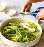 Snipping fresh chives over romaine lettuce salad with creamy dressing using Misen kitchen scissors