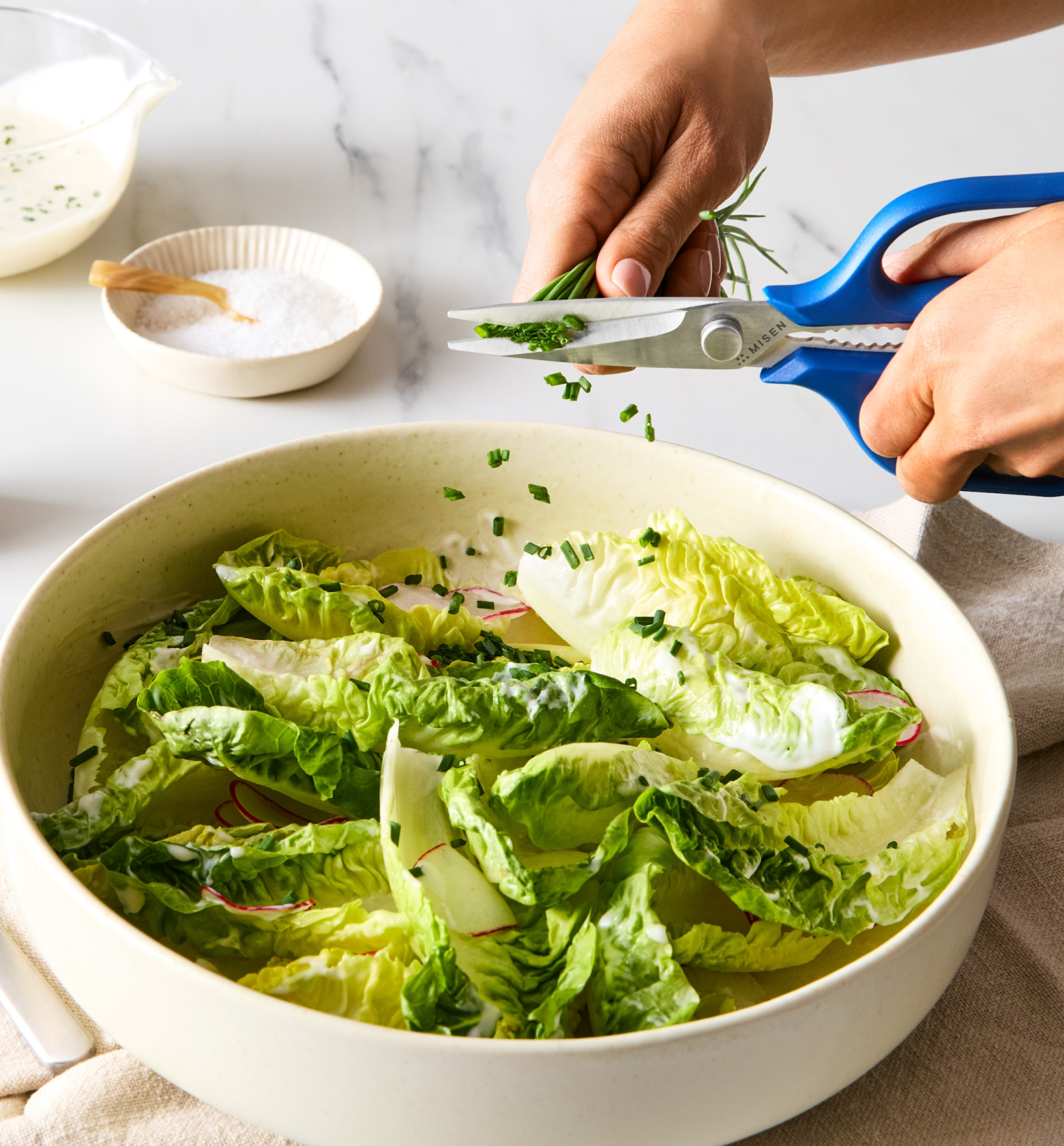 Snipping fresh chives over romaine lettuce salad with creamy dressing using Misen kitchen scissors