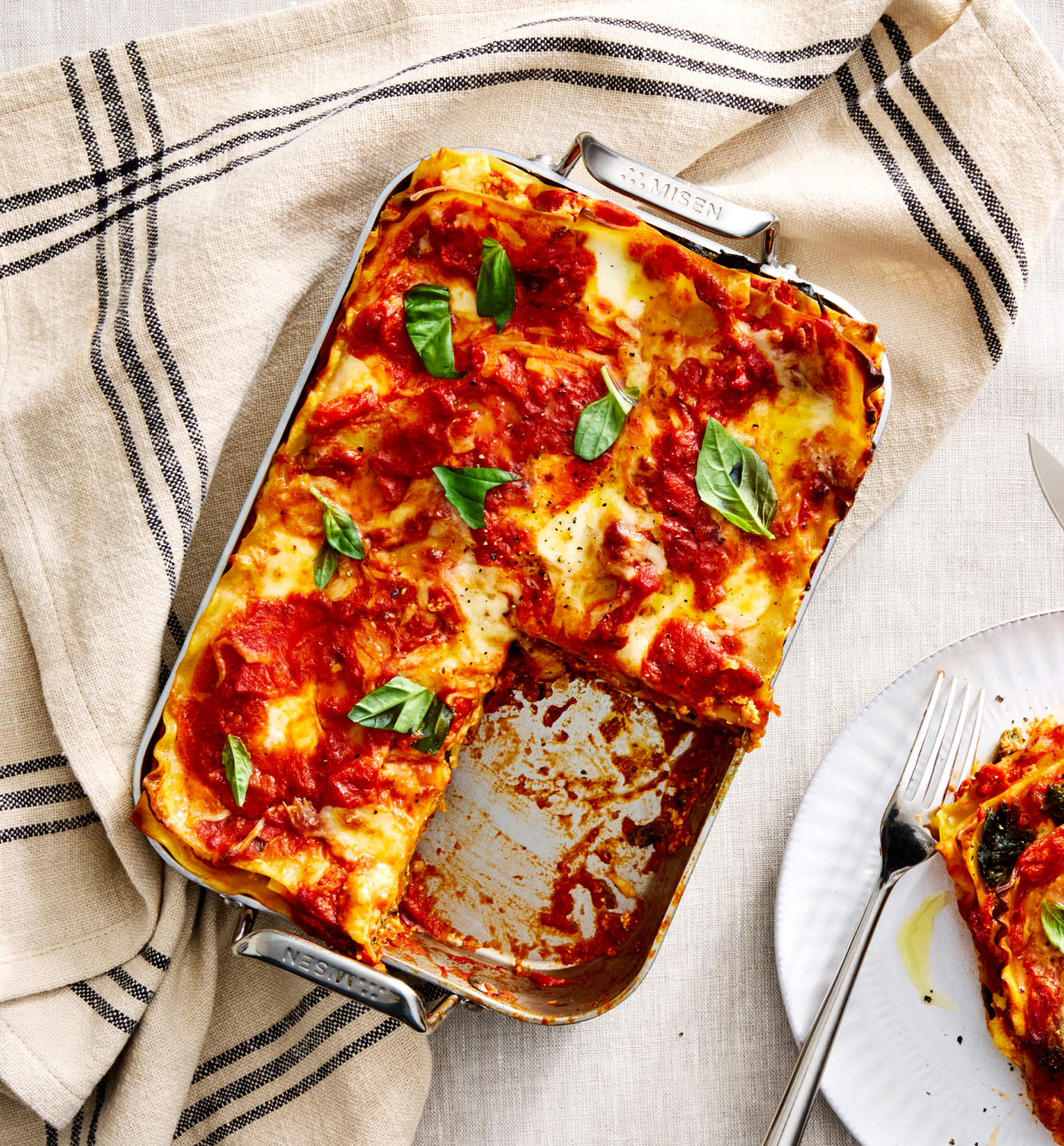 Homemade lasagna in Misen baking pan with tomato sauce and fresh basil