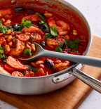 Shrimp and white bean tomato stew with fresh herbs in stainless steel pan