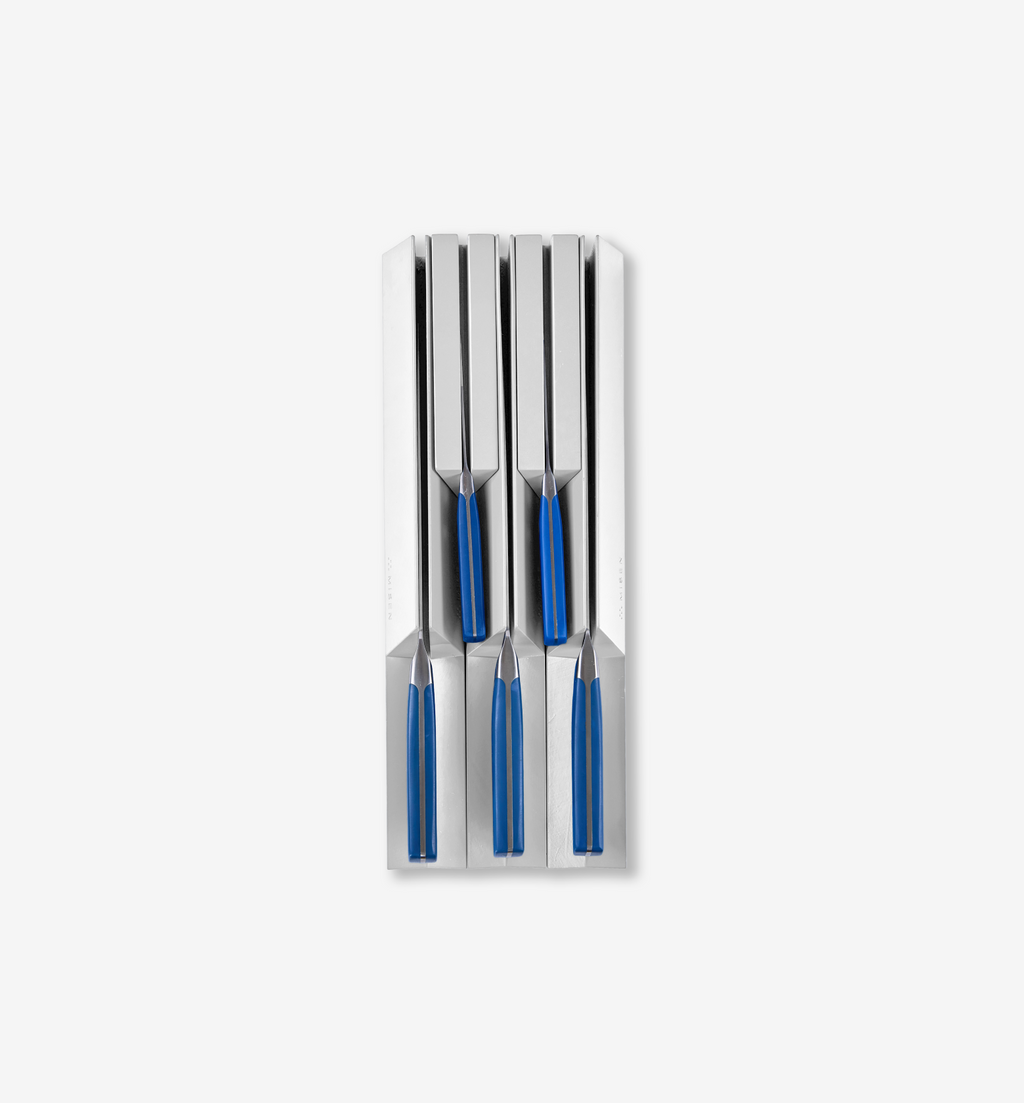 Set of four steak knives with blue handles stored in a stainless steel knife block drawer organizer