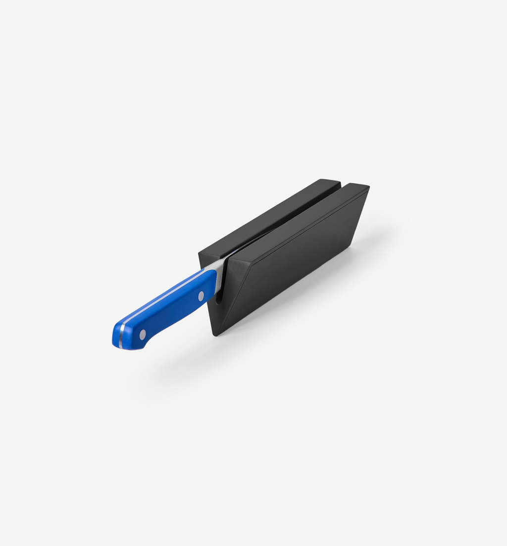 Kitchen knife with blue handle inserted into black knife sharpener block