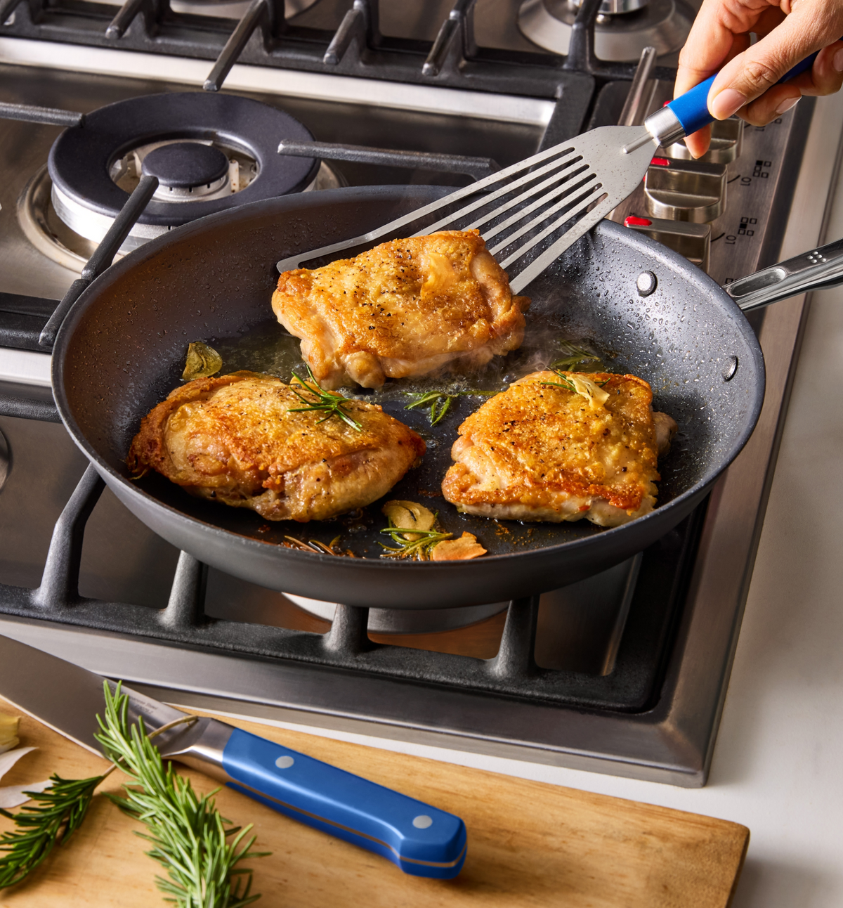 Golden crispy chicken thighs pan-seared with rosemary and garlic in nonstick skillet