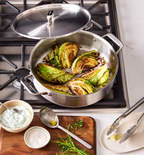 Seared cabbage wedges in Misen stainless steel braiser pan on gas stovetop with herb sauce