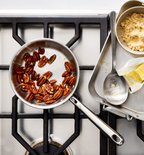 Toasted pecans in Misen stainless steel skillet with brown sugar and butter on gas stovetop
