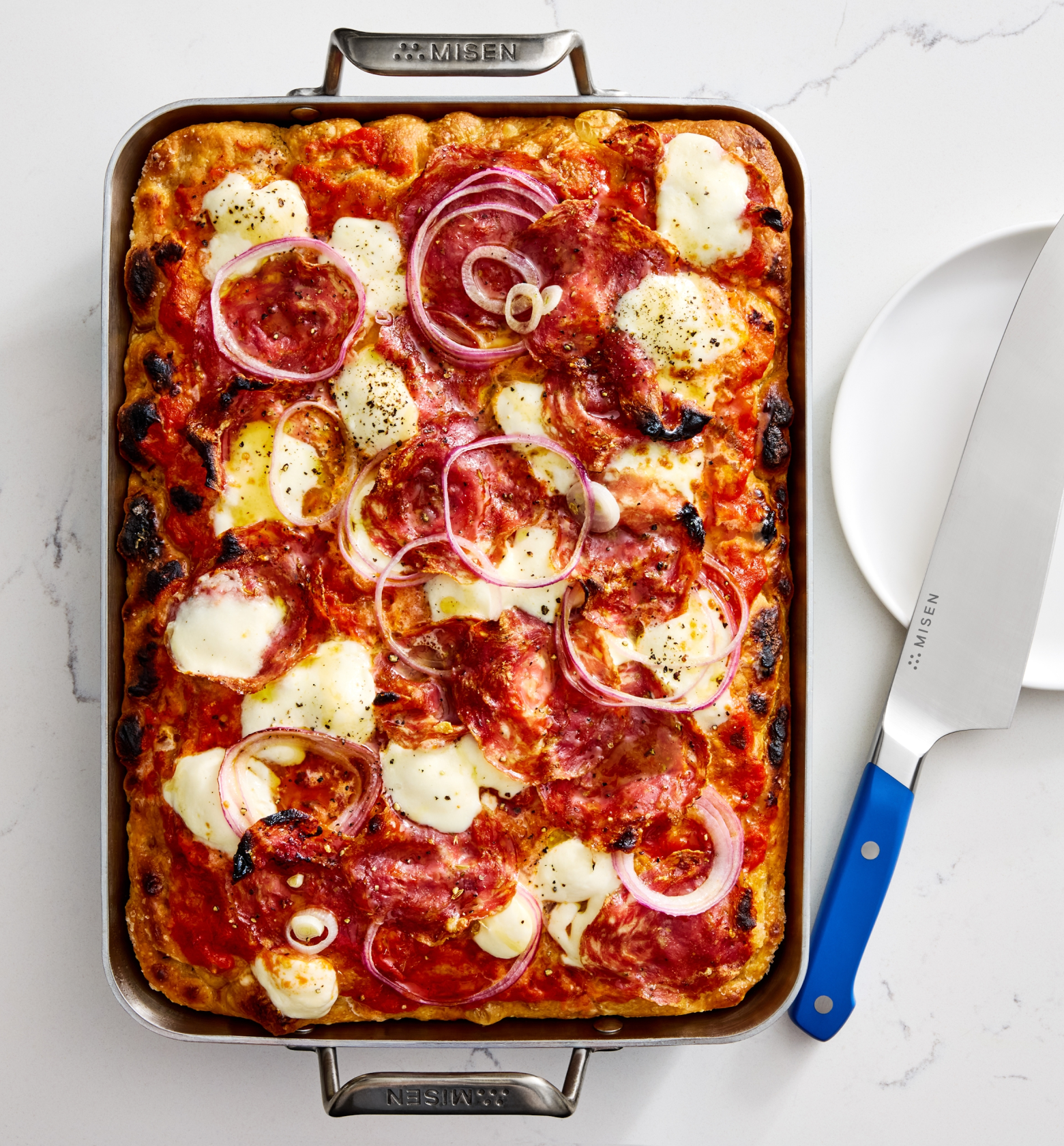 Detroit-style sheet pan pizza with mozzarella, salami, and red onion in Misen baking pan