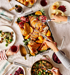 Thanksgiving turkey dinner spread with roasted brussels sprouts, cranberry sauce, and dinner rolls on holiday table