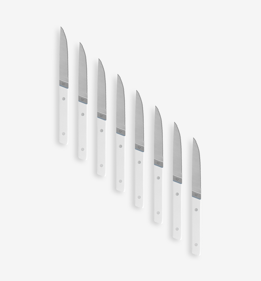 Set of 8 serrated steak knives with white handles arranged in a fan pattern