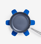 Nonstick frying pan resting on blue silicone pot holders trivet