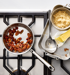 Misen stainless steel cookware with toasted pecans, brown sugar, butter, and measuring spoon on gas stovetop
