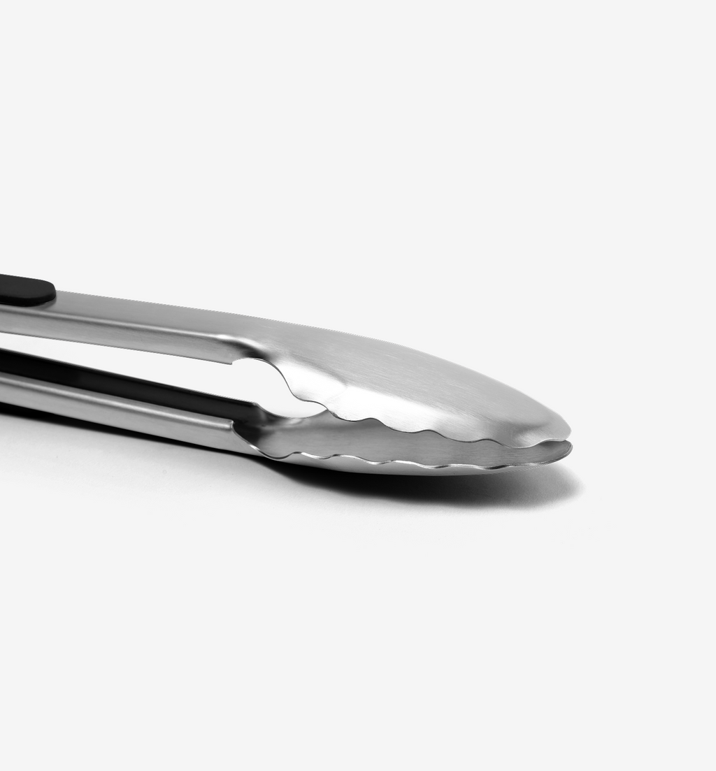 Stainless steel kitchen tongs with scalloped gripping edges close-up