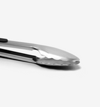 Stainless steel kitchen tongs with scalloped gripping edges close-up