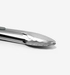 Stainless steel kitchen tongs with scalloped gripping edges close-up