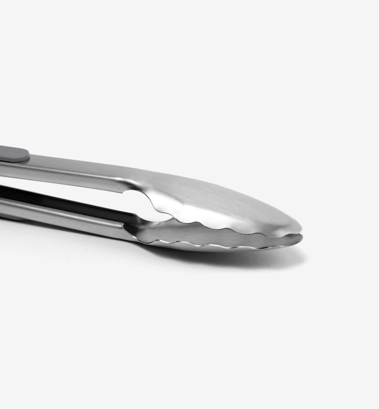 Stainless steel kitchen tongs with scalloped gripping edges close-up