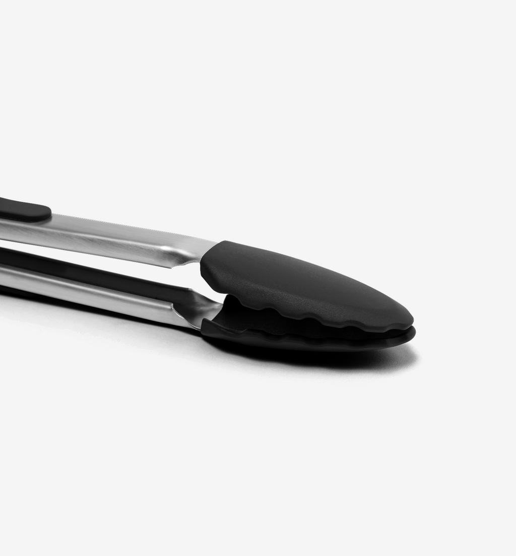 Stainless steel kitchen tongs with black silicone tips close-up