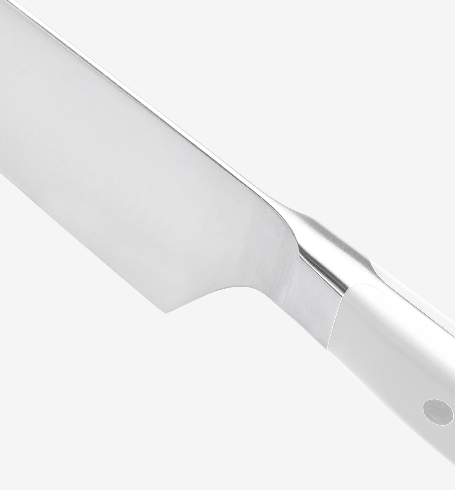 Chef's knife close-up showing stainless steel blade bolster and white handle