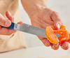 Using a blue short 6.5 serrated knife to supreme a blood orange.