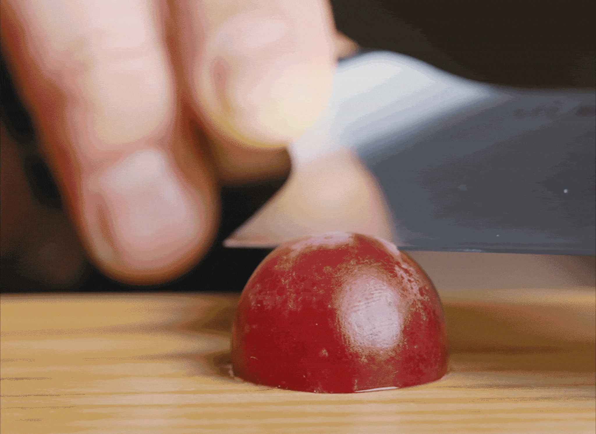Demonstrating how sharp a Misen Chef's Knife is by cutting a grape paper thin slices.