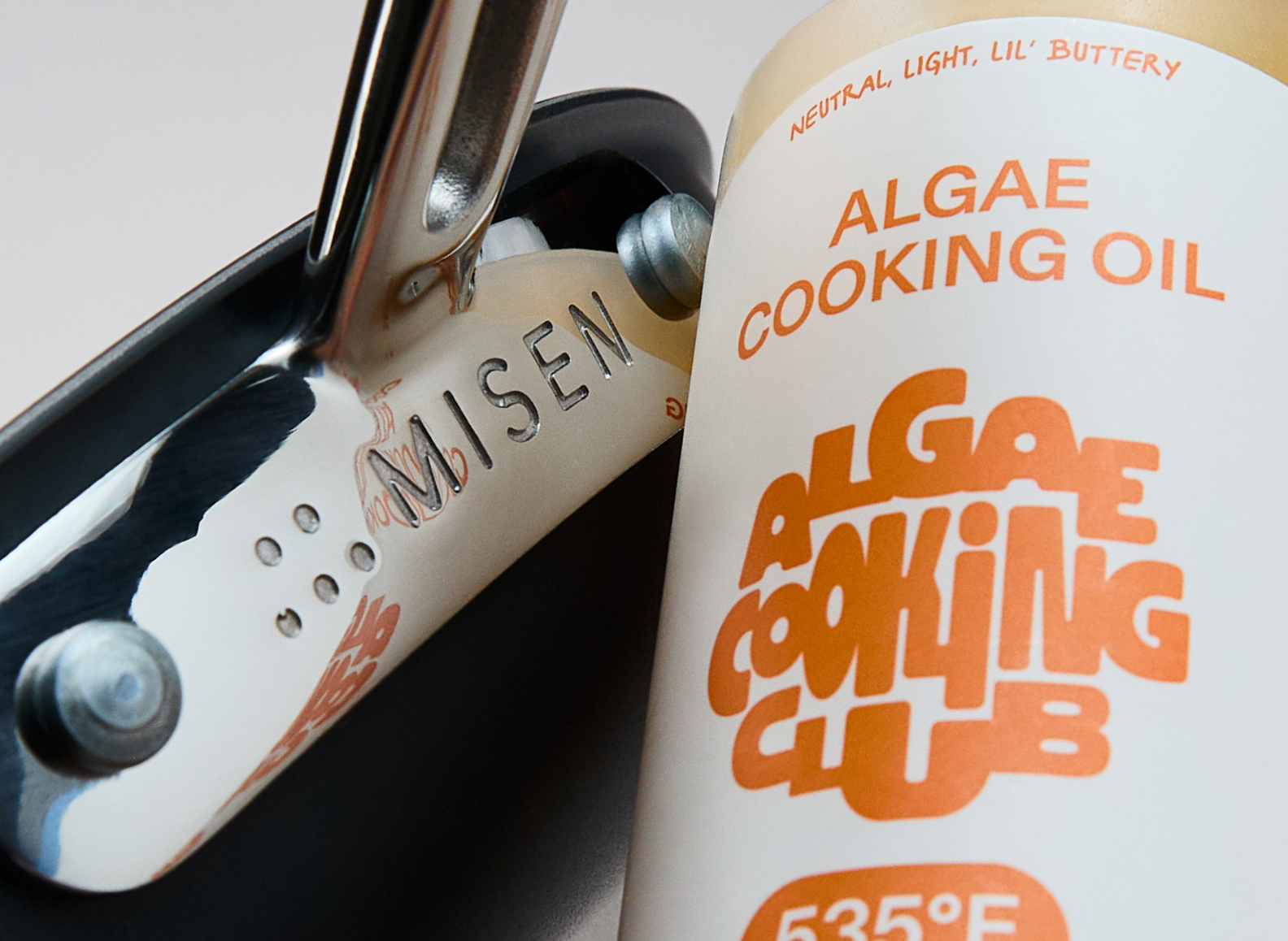 A close-up image shows a Misen branded Carbon Nonstick™ frying pan and a bottle of Algae Cooking Club Cooking Oil. The cooking oil is described as "neutral, light, lil' buttery" and has a smoke point of 535°F.