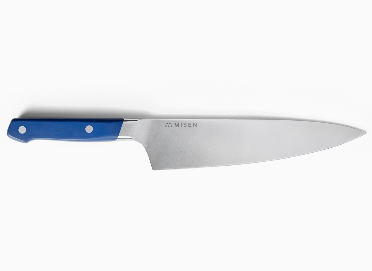 A Misen 8 inch Chef's Knife 2.0 with a blue handle and a silver ACUTO440 steel blade is shown on a white background. The Misen logo, five dots arranged in a triangle, is visible on the blade near the handle.