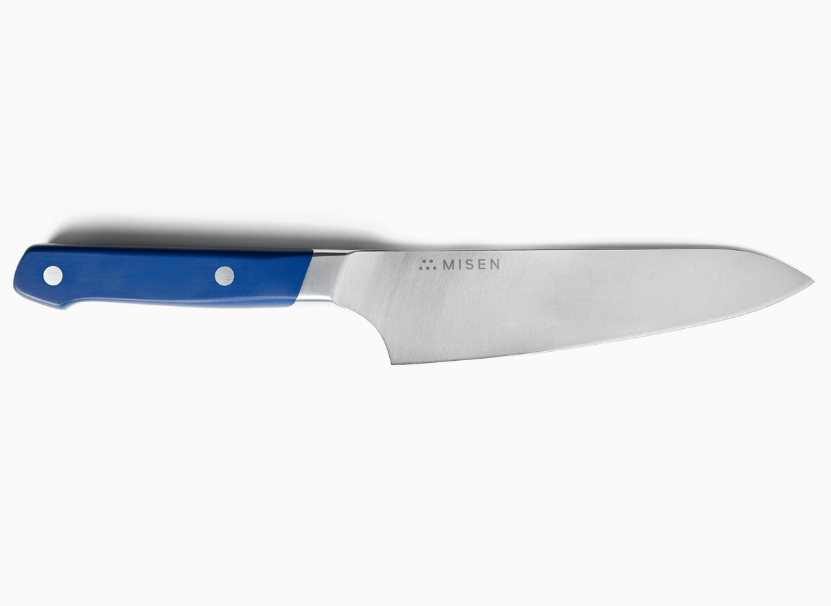 A Misen 6.5 inch Gyuto Knife with a blue handle is shown against a white background. The knife has a wide ACUTO440 steel blade that tapers to a sharp point, and the word "MISEN" is engraved on the blade near the handle. The handle has two visible rivets.