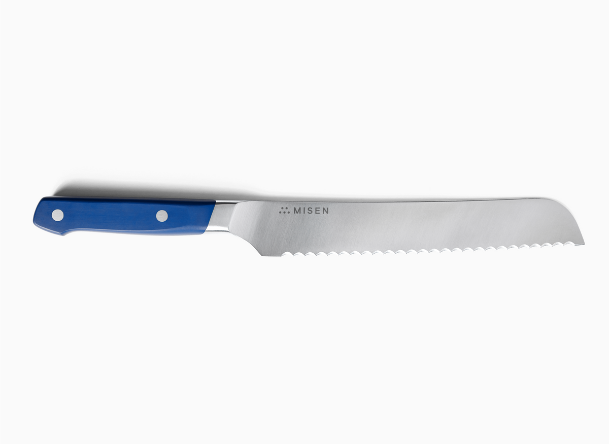 A top-down view of a blue-handled 5 inch Serrated Knife 2.0 against a white background. The knife is positioned horizontally with the handle on the left and the serrated blade extending to the right. The ACUTO440 steel blade is silver-toned and features the "MISEN" logo and name. The handle is a rich blue with two silver rivets visible.