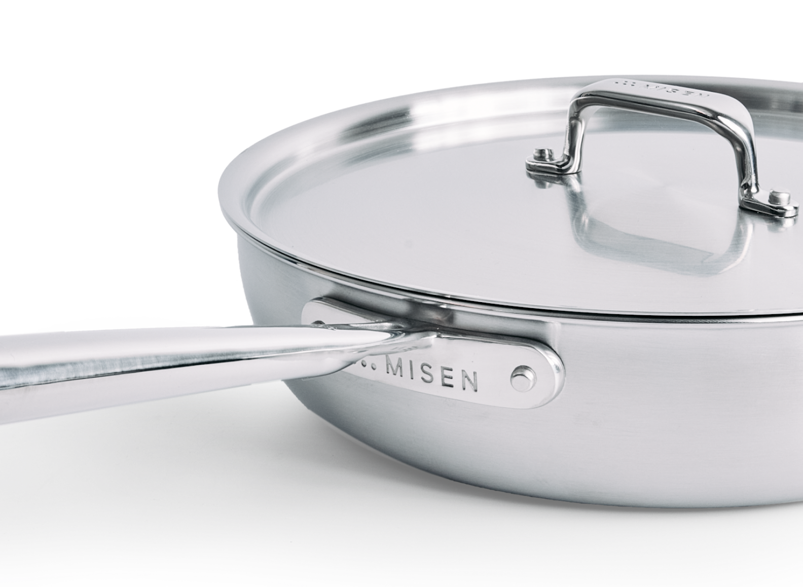 A close-up shot of a 4 QT stainless steel pan with a lid is depicted, showing the handle attachment plate on the side of the pan embossed with "MISEN" and the word "MISEN" also visible on the lid's handle.
