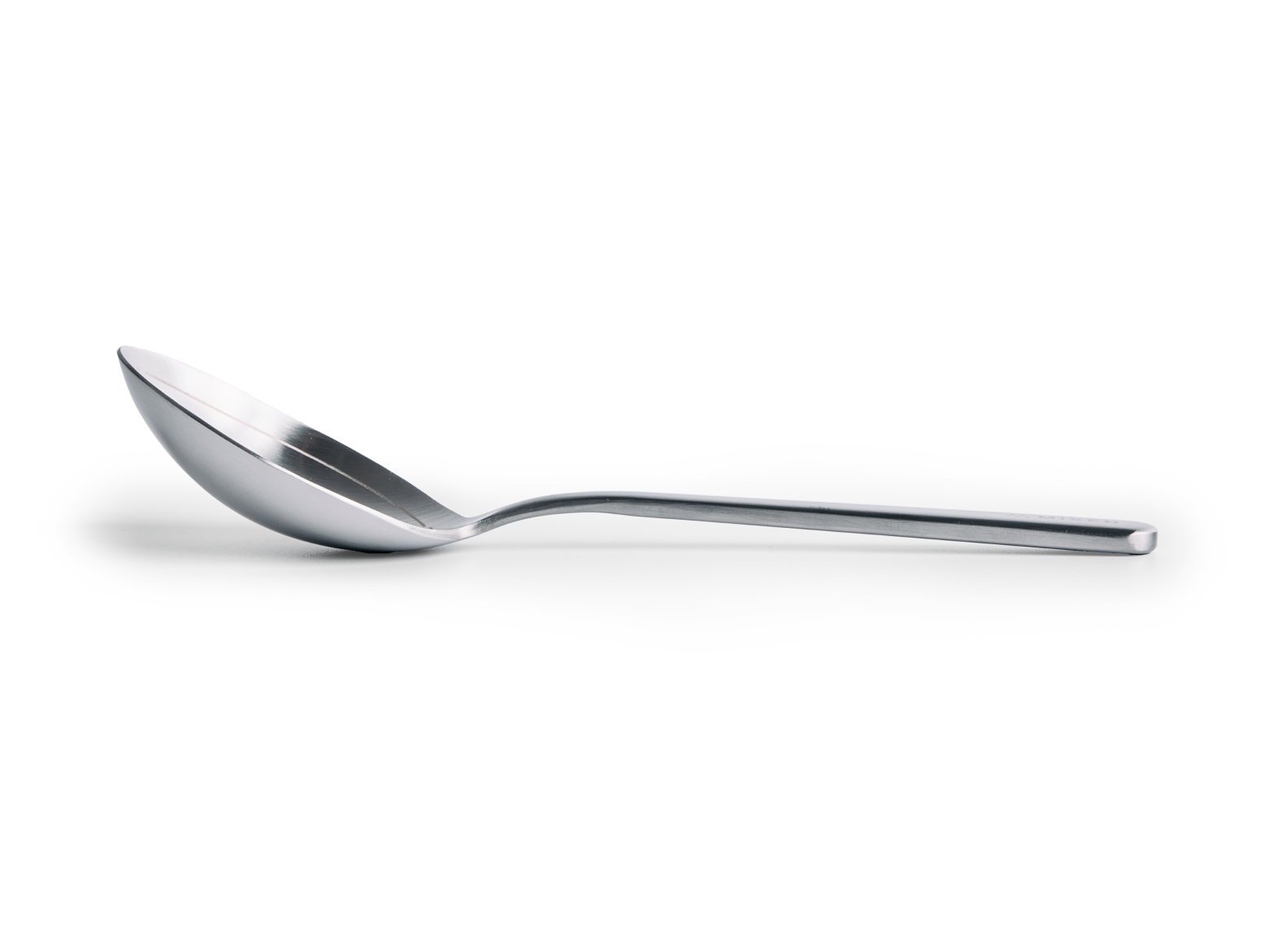 A side profile of a polished stainless steel Misen Measuring Spoon resting horizontally on a white surface. The spoon has a shallow bowl and a long, straight handle.